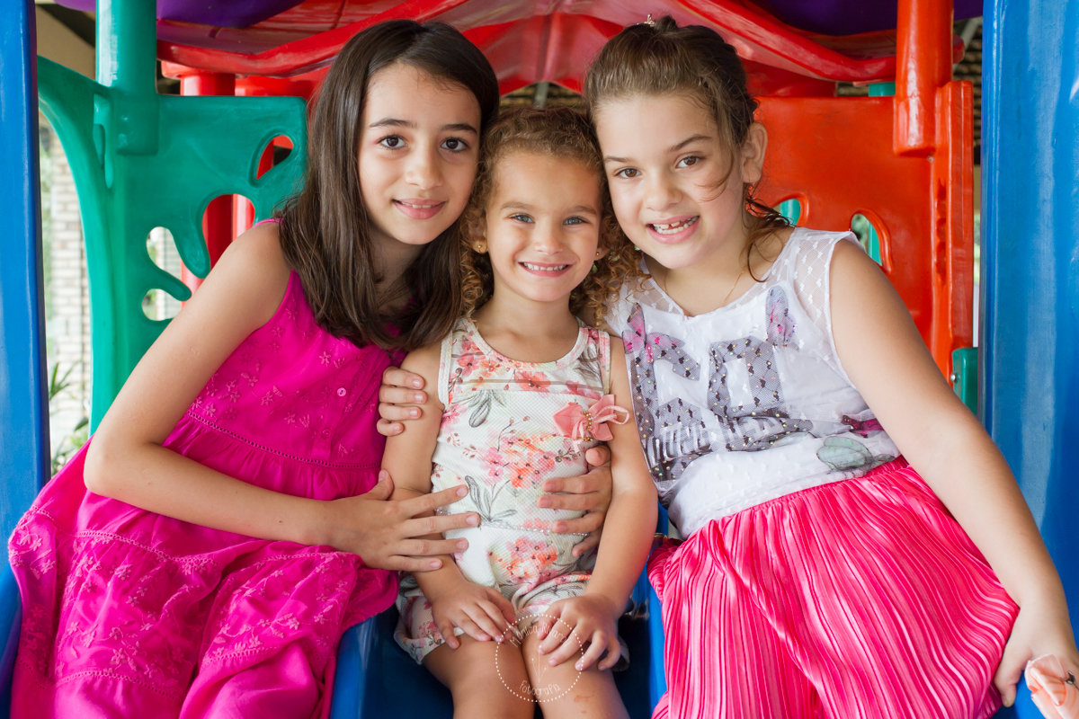 A Luisa esta com suas primas em cima de um brinquedo e sorrindo para a foto