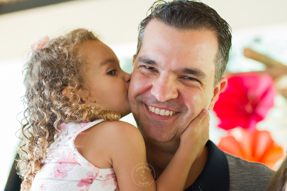 A Luisa esta dando um beijo cheio de carinho na bochecha do seu pai 