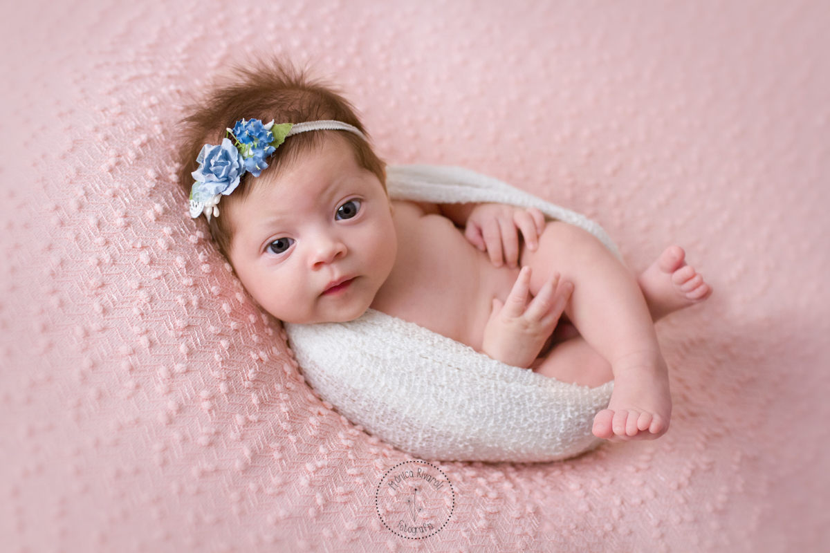 Deitadinha em uma mantinha, a Catarina esta acordada olhando para a câmera