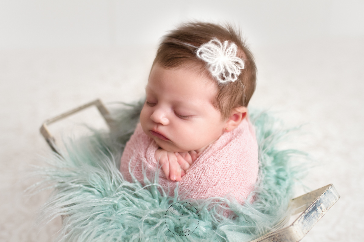 Com uma tiarinha branca, enrolada em um paninho fofo, a Catarina dorme