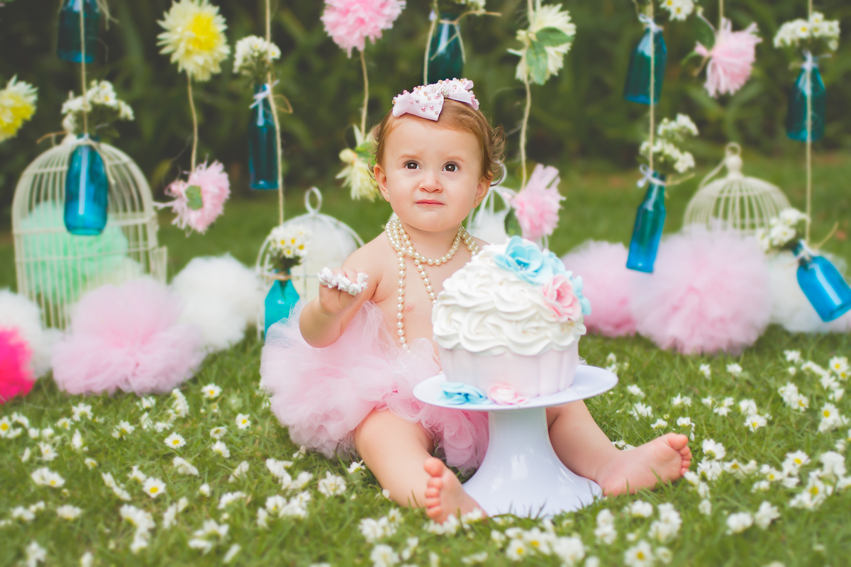 Agora ela está sentadinha na grama e atrás do bolo