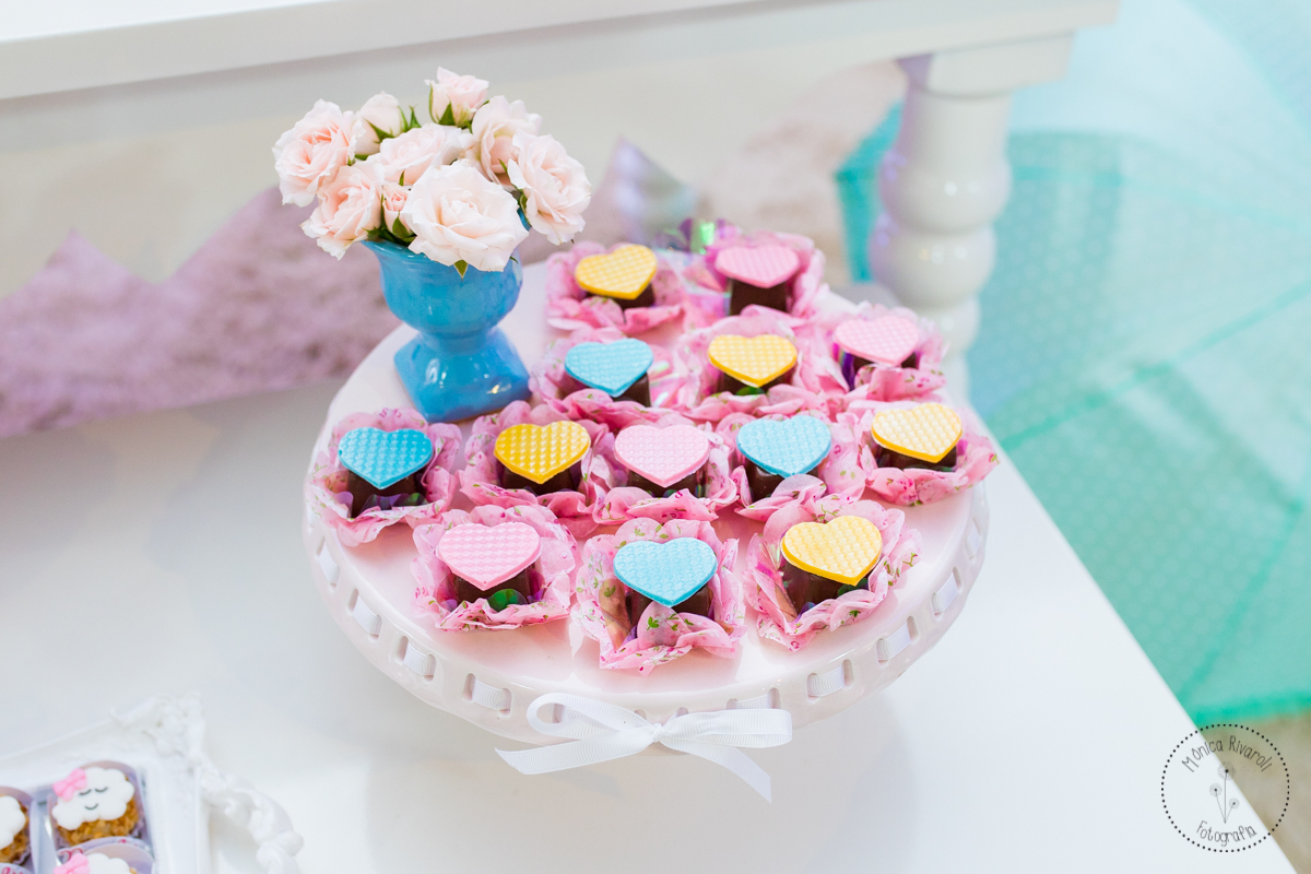 Aparador branco com docinhos de chocolate decorados com corações coloridos