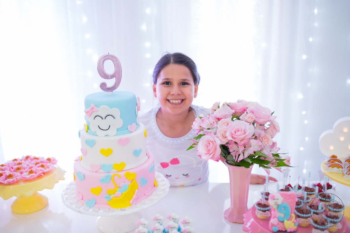 Nicoli atrás da mesa de doces, ao lado do bolo