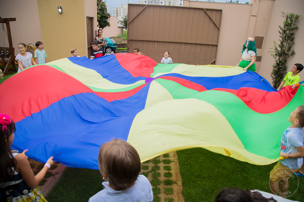 Imagem aberta das crianças segurando um pano maior junto com os palhaços