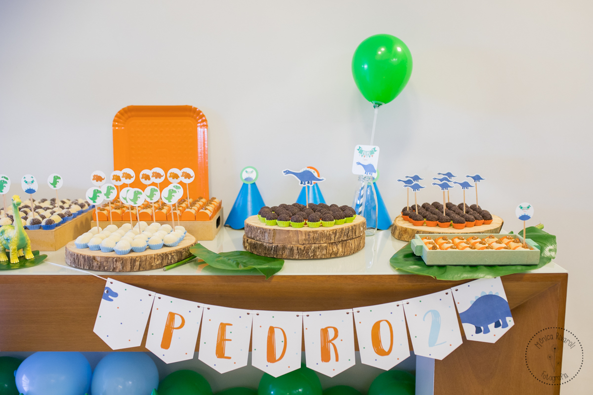 Close na mesa de doces com decoraçaõ de dinossauros 