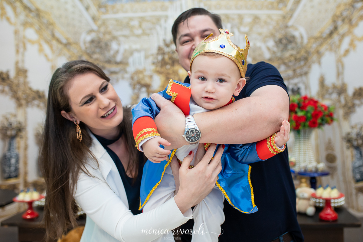 O papai esta brincando de aviãozinho com o Miguel, ao lado da mamãe.
