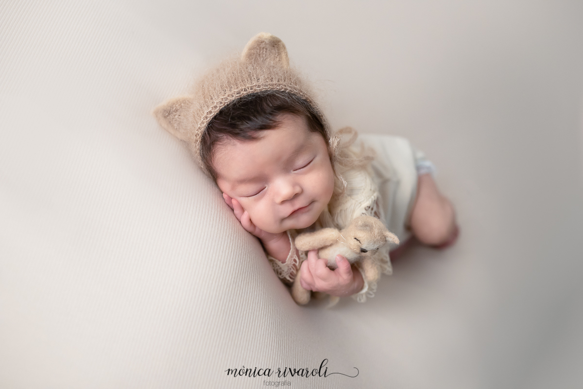 De ladinho e com uma das mãos na bochechinha, a bebê fotografada por Mônica Rivaroli, segura um gatinho de feltro e usa uma touquinha de gatinho