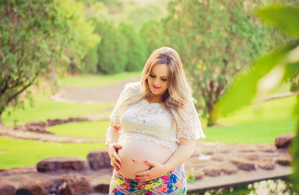 Em um fundo ensolarado, a mamãe acaricia seu ventre e conversa com sua bebê