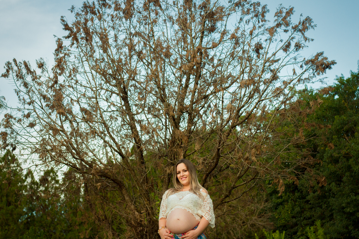 Em frente a uma árvore grande e robusta, a mamãe sorri