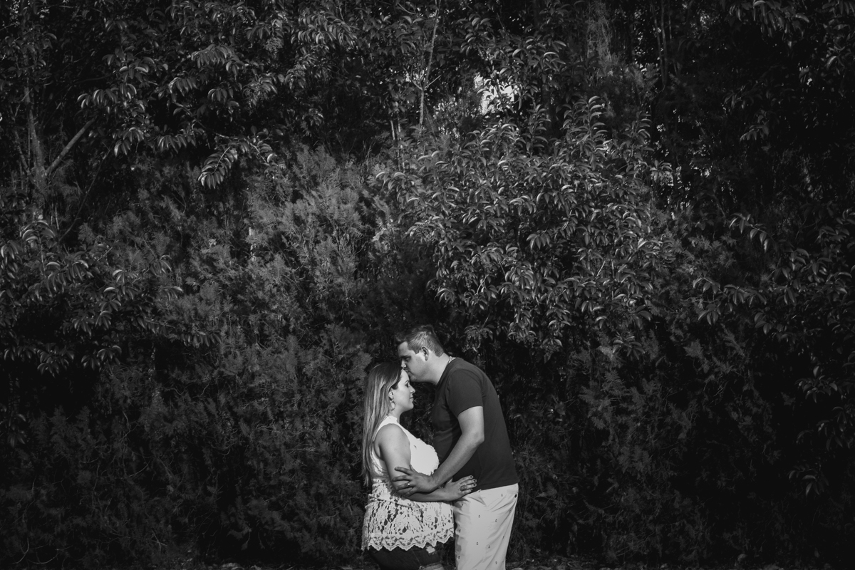 Sobre luzes e sombras, a mamãe receb um beijo de seu esposo enquanto acariciam o ventre