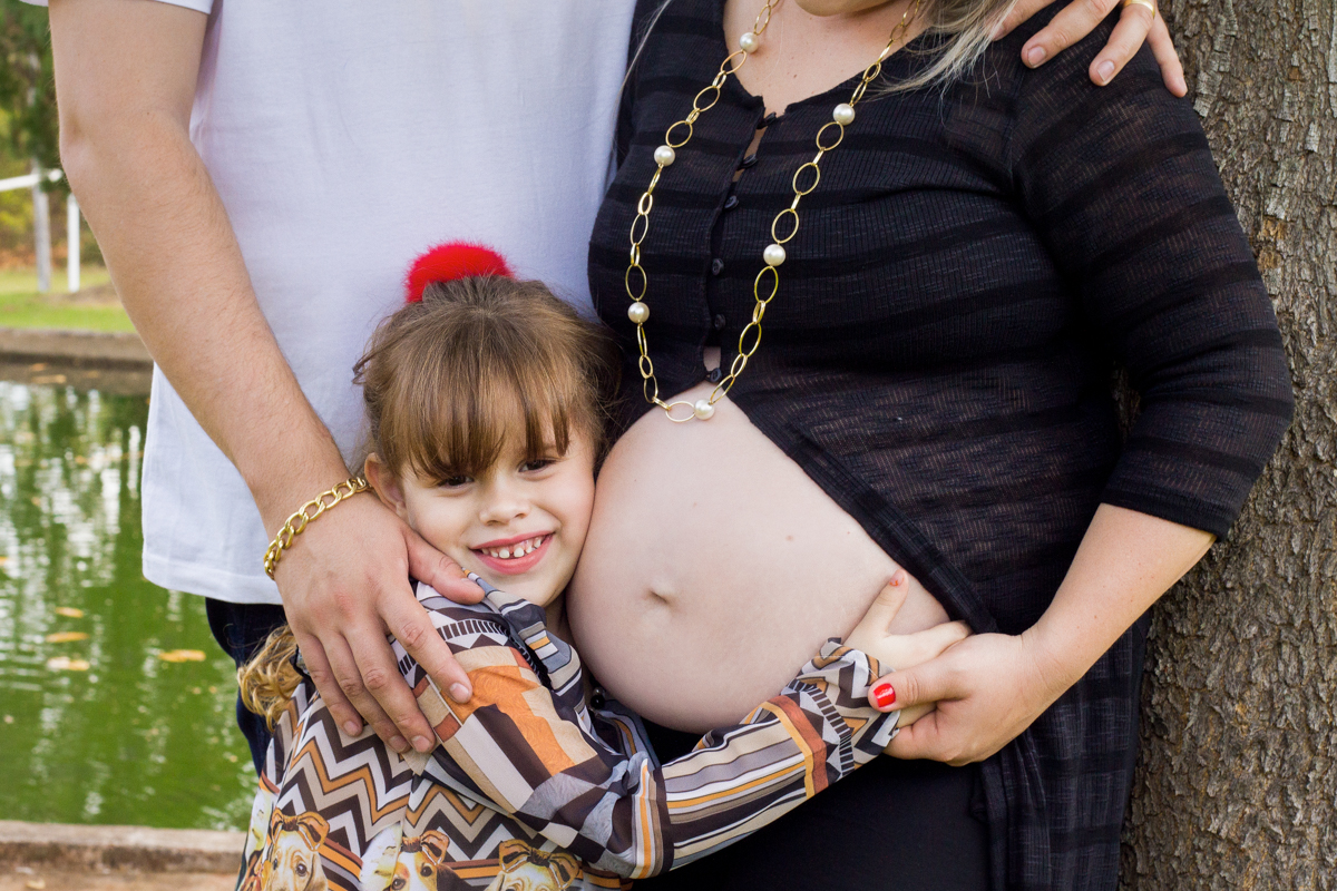 A irmã mais velha abraça o ventre da mamãe e sorri
