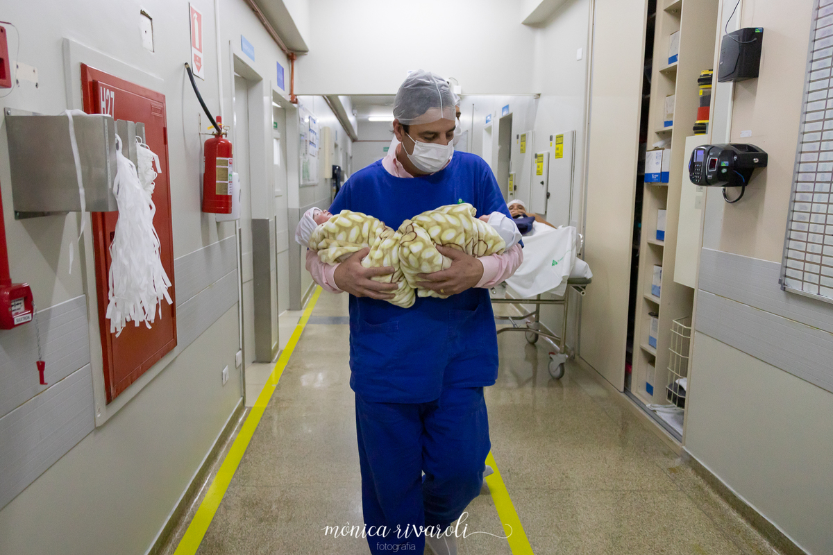 Idelber leva as Anas para o berçário. Fotografo de parto Mônica Rivaroli fotografia em Maringá. Tentantes, infertilidade, trombofilia endometriose. Ele segura uma em cada braço e olha profundamente as meninas.