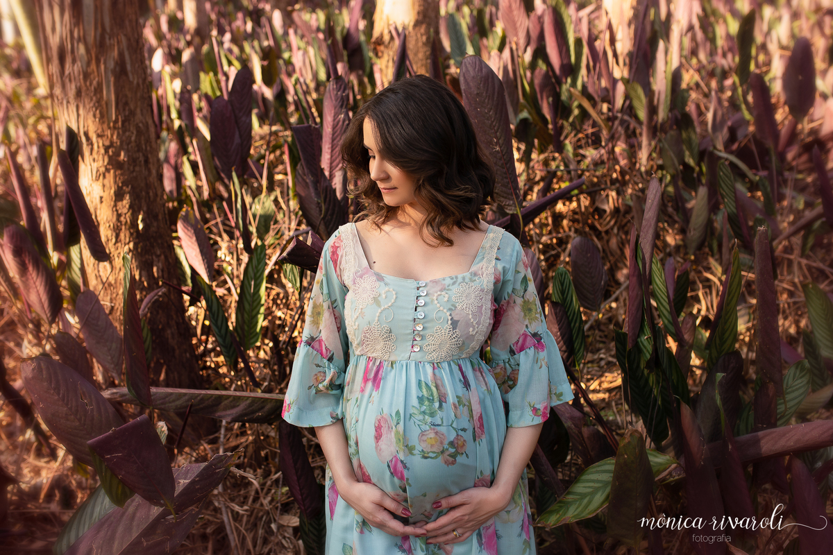 Um vestido azul claro com flores rosas e lilas ficou um encanto na folhagem verde e roxa escolhida pelo casal! A mamãe segura a barriga com um olhar bem charmoso e cheio de sentimento! Os ensaios mais lindos para  Book de gestante Monica Rivaroli 