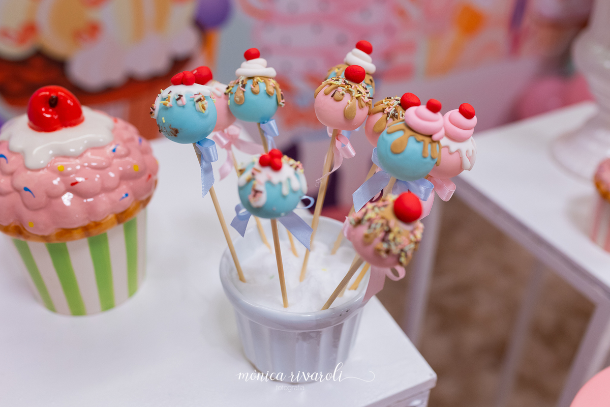 Docinhos que são chamados de cakepop em forma de bombons com uma cereja em cima