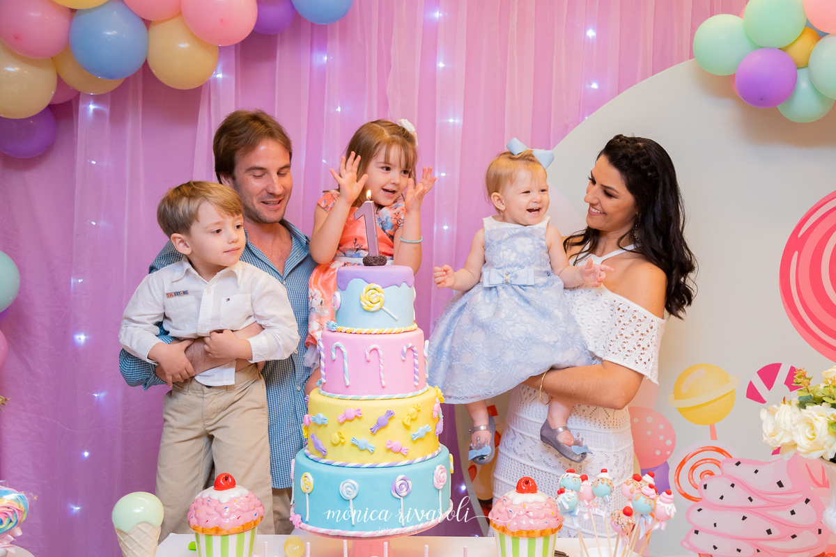 Eles cantam parabéns. A Irmã da mariah, bate palminhas enquanto o papai, a mamãe e a Mariah sorriem