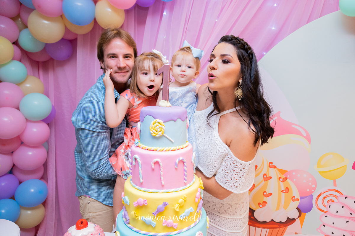 Foto mais próxima ao rosto da família. Todos estão assoprando a velinha do bolo após os parabéns