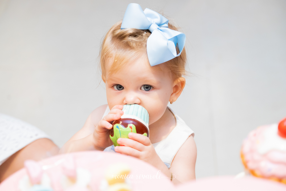 Uma foto bem fechada no rostinho da Mariah, que segura um docinho de porcelana que estava na mesa da decoração