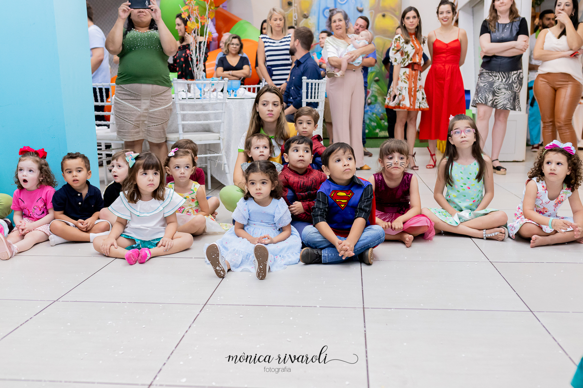 AS CRIANÇAS FICARAM QUIETINHAS SENTADINHAS NO CHÃO ASSISTINDO A APRESENTAÇÃO