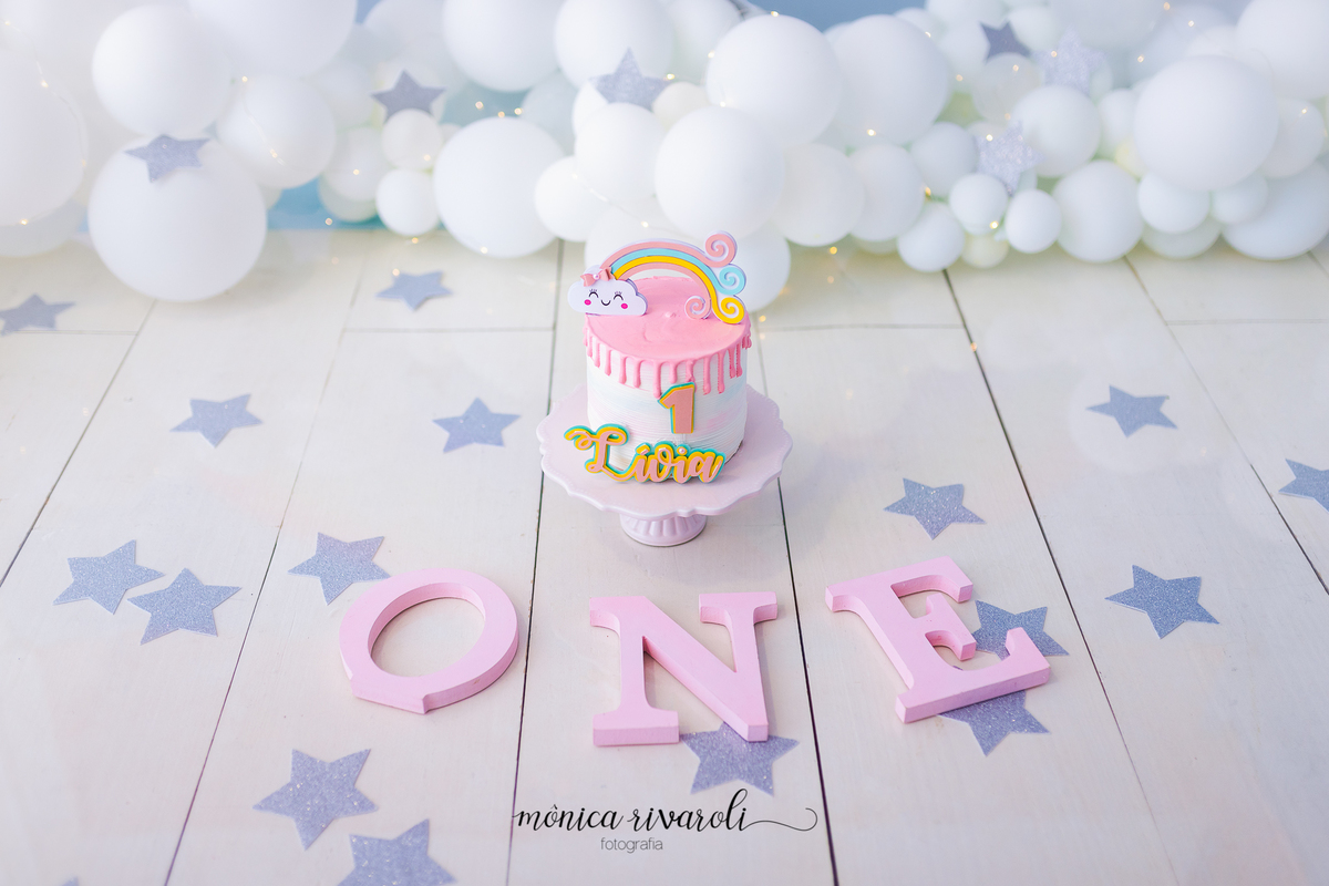 ESTRELINHAS PRATEADAS DEIXAM O CENARIO LINDO E AS LETRAS O N E EM ROSA BEM SUAVE COMPLETAM O CENARIOS REMETENDO A PALAVRA EM INGLES ONE.