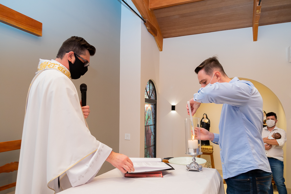 Padrinho sobe até o altar para acender a vela de batismo