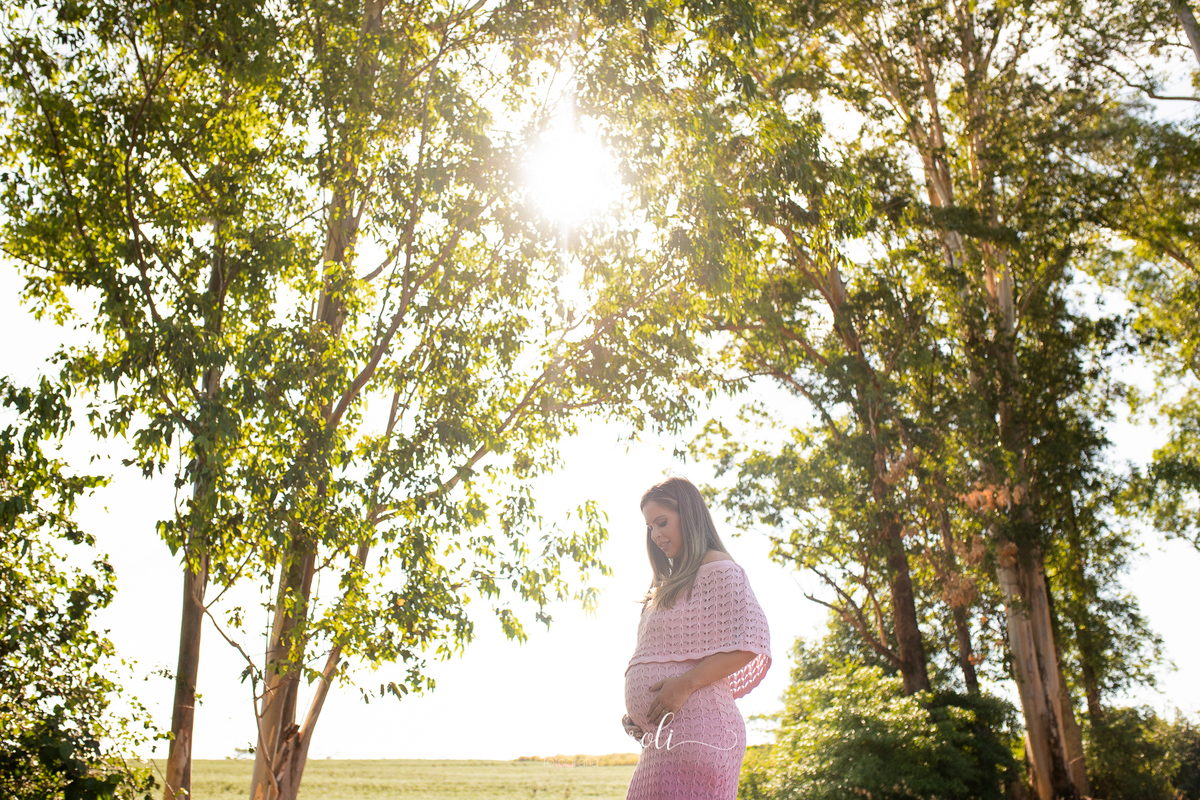 Em um lugar aberto com muitas árvores, a gestante está no centro da foto com a mão na barriga e olhando para baixo.
Ensaio Gestante
Fotografado por Mônicas Fotografia em Maringá-PR
