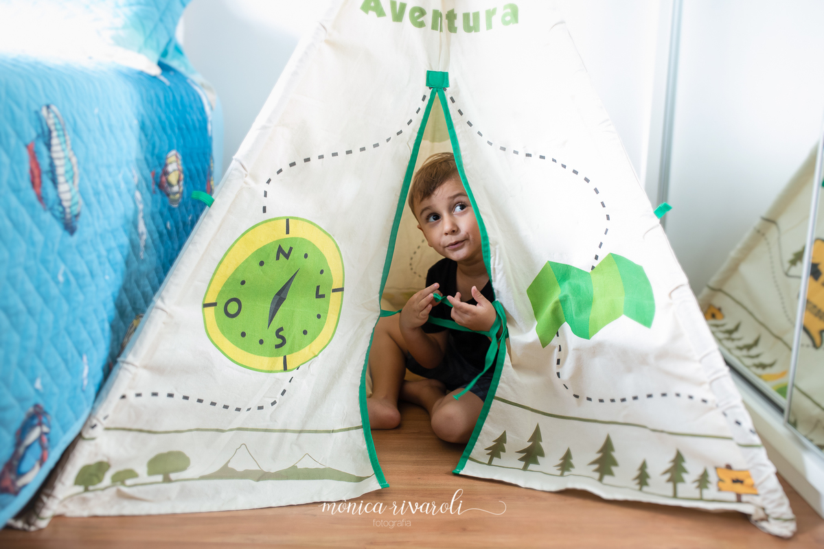 O irmão mais velho, chamado Otávio, está sentado dentro de uma cabana de brinquedo e olhando para fora.
Fotografado por Mônicas Fotografia em Maringá-PR