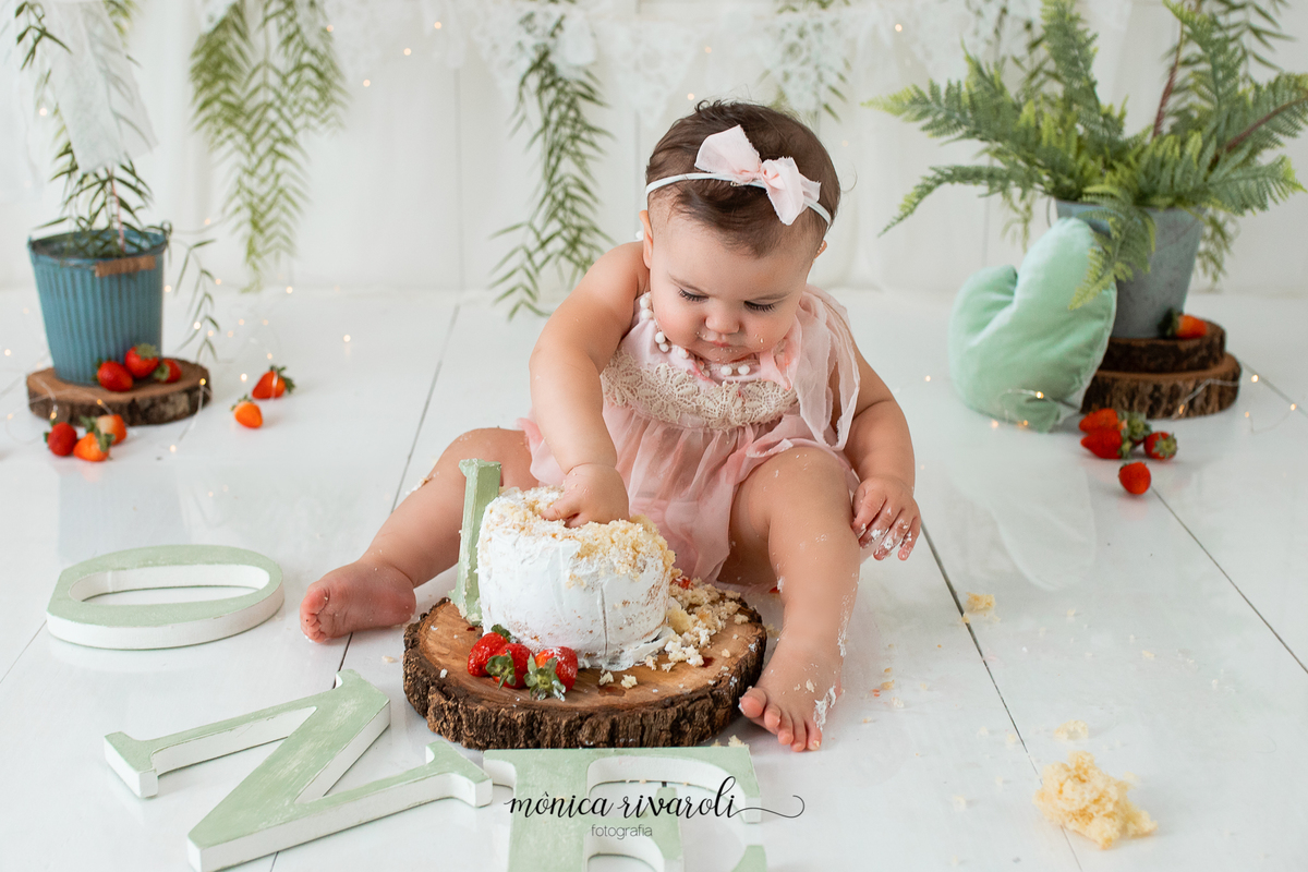 No cenário de Smash, a bebê está sentada olhando para o bolo e colocando a mão nele.
Ensaio Smash The Cake
Fotografado por Mônicas Fotografia em Maringá-PR
