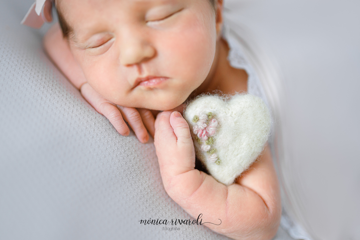Na mesma posição, está foto é um close mostrando a mãozinha e o coração de pulúcia. 