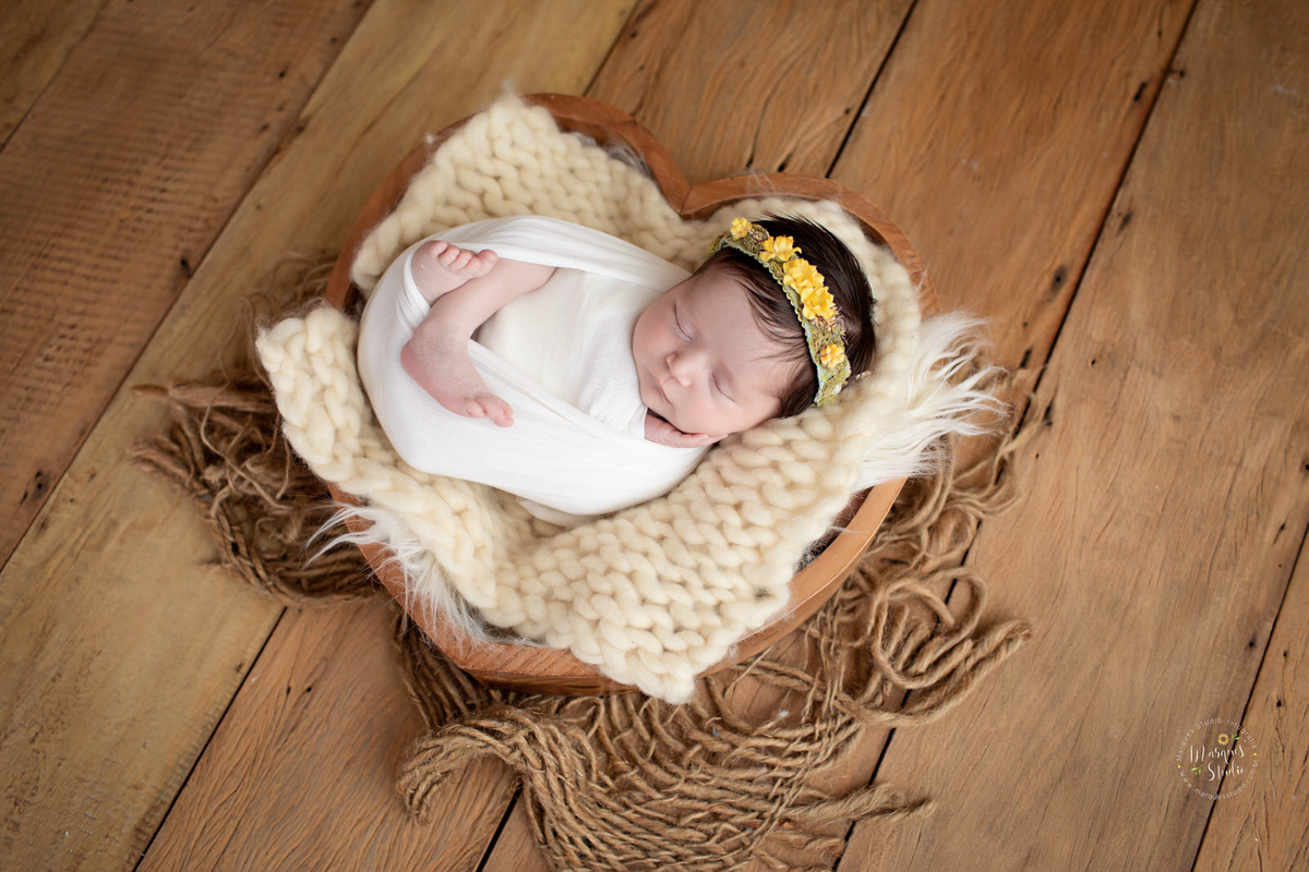 Ensaio feito estilo Newborn da Betina, Em Studio Localizado na Vila Madalena  - São Paulo, SP. Na foto a bebê está enrolada em um wrep branco. usando uma tiara amarela na cabeça e está dentro de um coração de madeira.