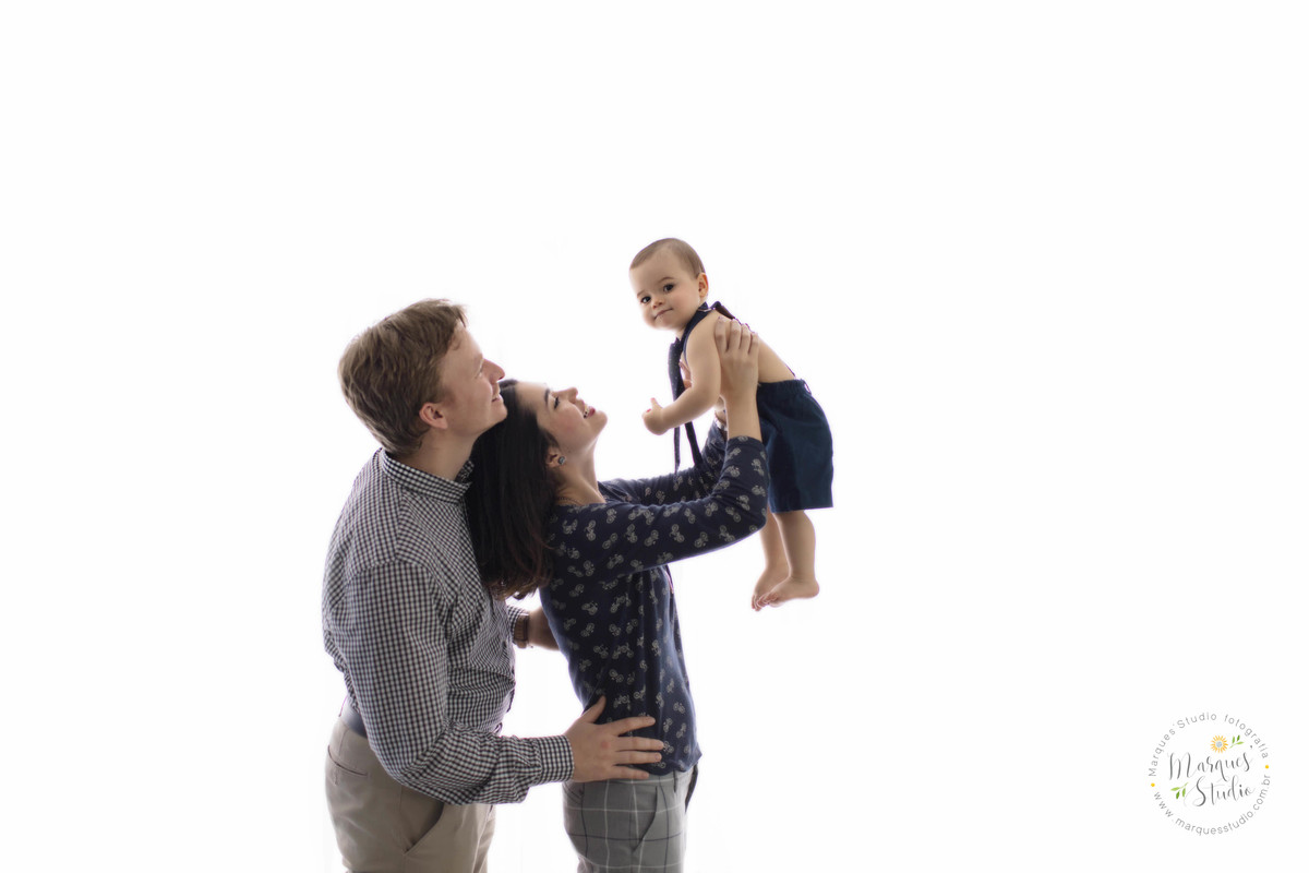 Fotografia de sessão de acompanhamento de bebê com a mamãe e o papai em fundo fotográfico branco e todos sorrindo no studio na Vila Leopoldina São Paulo SP