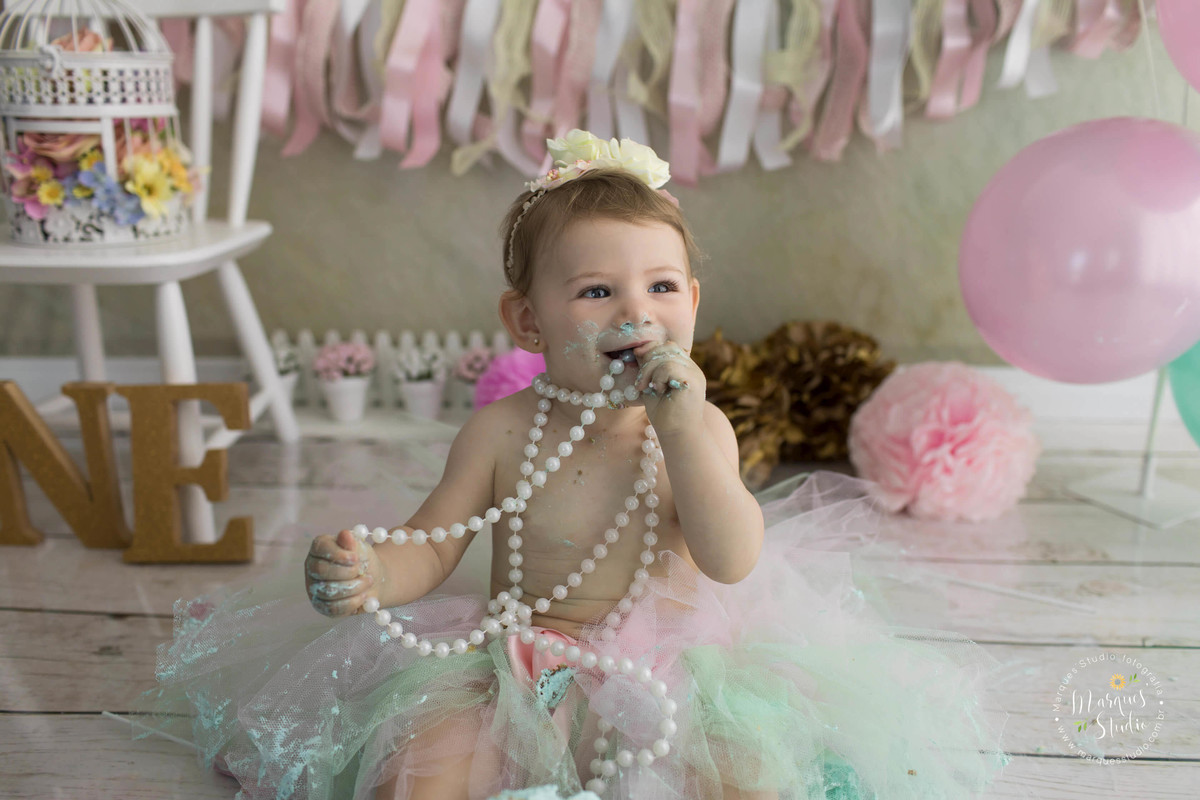 Ensaio fotográfico realizado na Vila Leopoldina SP no studio de fotografia para a sessão de smash the cake nas cores rosa e Tiffany para uma linda menina de 12 meses ela está sorrindo e está usando um lindo colar de pérolas e tiara com flores na cabeça