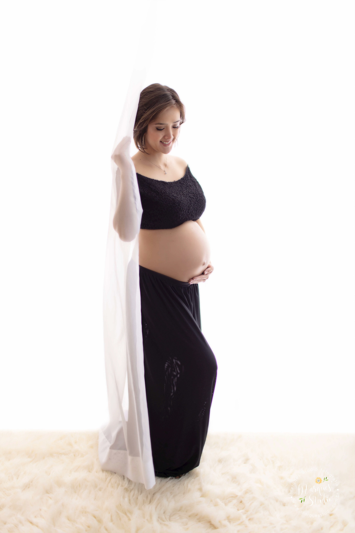 Foto feita em studio fotográfico localizado na Vila Leopoldina São Paulo SP para o ensaio gestante da Thais ela está usando um lindo conjunto de top e saia preto ela está posicionada de perfil e sua mão esquerda está sobre sua barriga de gestante