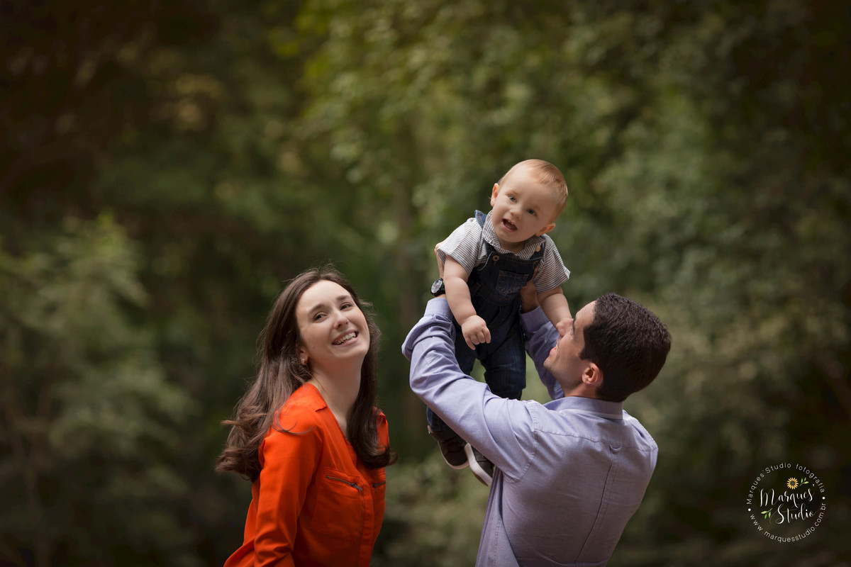 Fotografia de sessão de acompanhamento de bebê com a mamãe e o papai em um lindo parque, todos sorrindo na sessão fotografica,  na Vila Leopoldina São Paulo SP, ao fundo uma linda arvore com flores e folhas