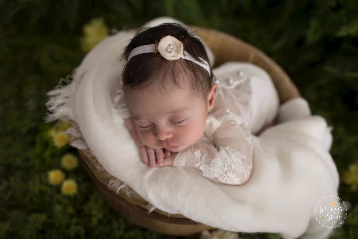 foto de bebê no jardim realizado no nosso studio fotográfico em São Paulo SP Vila Madalena, a bebê está dormindo com as mãozinhas no rosto, em sua cabeça ela usa uma linda headband de florzinha.