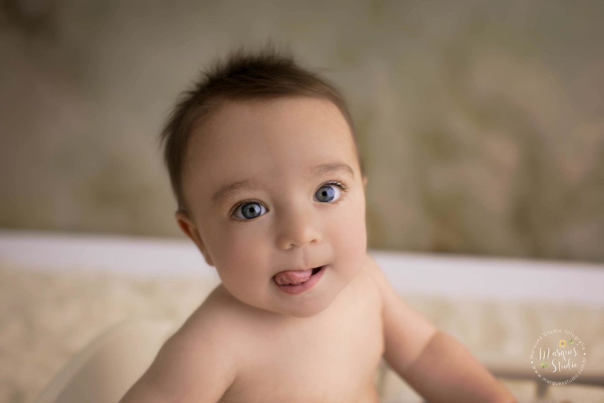 Fotografia do ensaio de acompanhamento de 6 meses do Enrico, na foto ele está com a língua pra fora, e com o rostinho feliz, o estúdio fotográfico fica localizado no Morumbi, São Paulo, SP, a foto está com close no rosto.