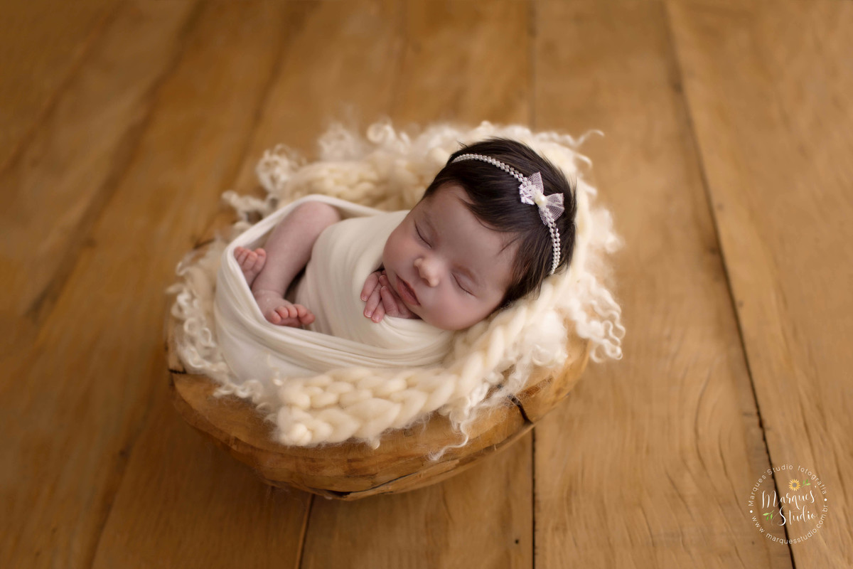 Foto feita para o ensaio newborn da Isabela, feito no nosso studio localizado na Vila Sumaré, São Paulo, SP. A Bebê está no wrap, de barriga pra cima, no fundo fotográfico de madeira.