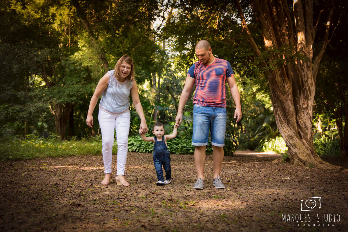 Foto de uma linda família em seu ensaio fotográfico, a mamãe o papai e o bebê estão caminhando de mãos dadas em um lindo parque, localizado na zona Oeste de São Paulo, Osasco, SP. Esse ensaio fotográfico foi feito para a sessão de Smash the Cake do Pedro.