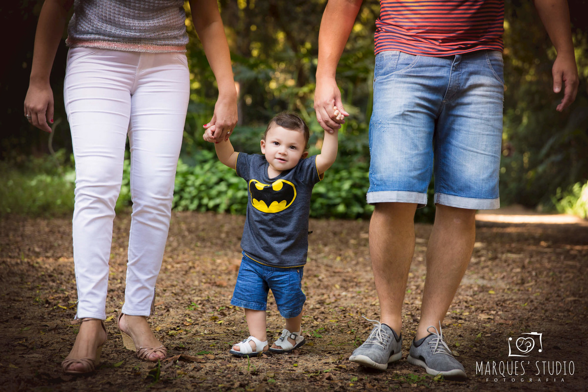 Fotografia de uma linda família em seu ensaio fotográfico, a mamãe o papai e o bebê estão caminhando de mãos dadas em um lindo parque, localizado na Vila Perdizes, São Paulo, SP. Esse ensaio fotográfico foi feito para a sessão de Smash the Cake do Pedro.