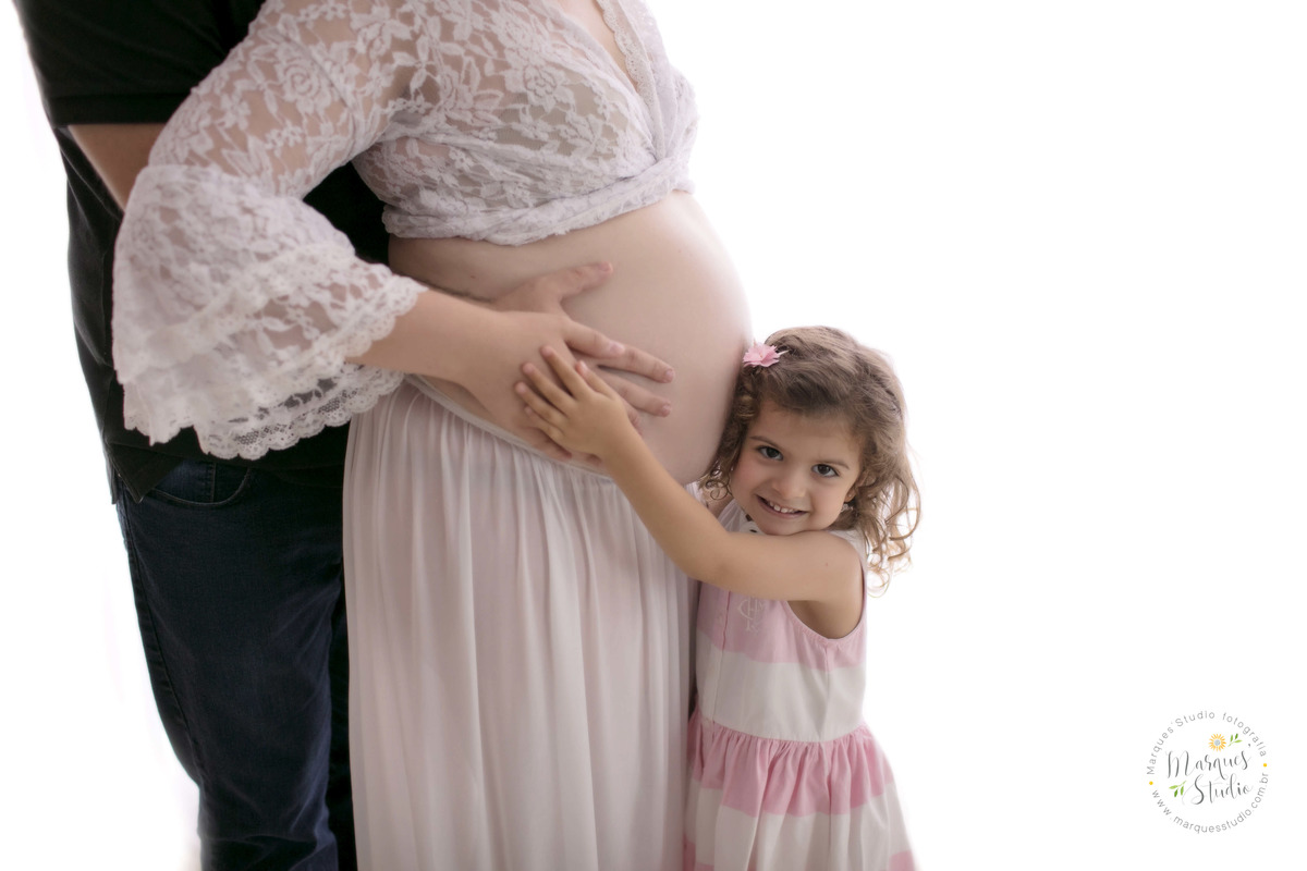 Foto feita para o ensaio de gestante da Juliana Selpa, no studio na Vila Leopoldina, São Paulo, SP, na foto está o papai abraçando a mamãe e a filha mais velha bem abraçadinha na barriga  da mamãe, ela está dando um lindo sorriso.