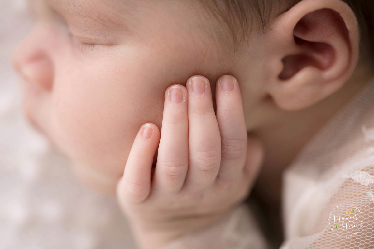 Foto feita do detalhe da mãozinha esquerda no rosto da bebê recém-nascida Isadora de 18 dias, em seu ensaio Newborn, fotografia feita no studio localizado no Morumbi, São Paulo, SP.