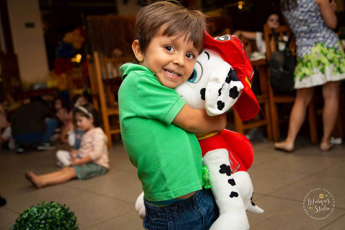 Foto tirada no aniversário do Joaquim de 4 anos, na foto temos uma criança feliz e sorridente abraçando um ursinho de pelúcia da patrulha canina. O buffet fica na Av. Consolação, São Paulo, SP