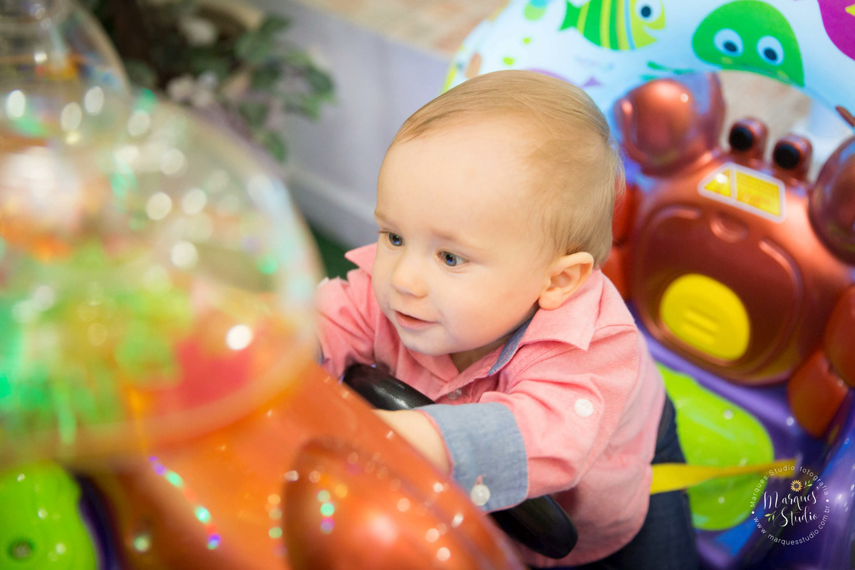 Foto feita no aniversário do Benjamin de 1 ano. No salão  de festas que fica localizado na Vila Madalena - São Paulo, SP. Na foto o aniversariante está brincando sorridente, em um carrinho da cor roxa.