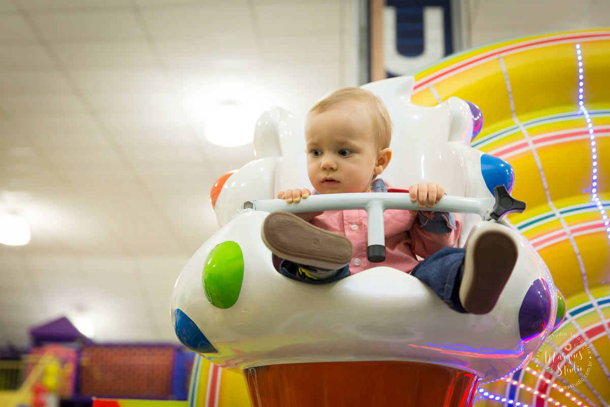 Foto feita no aniversário do Benjamin de 1 ano. No salão de festas que fica localizado em Perdizes - São Paulo, SP. Na foto o aniversariante está brincando em um brinquedo gira gira.
