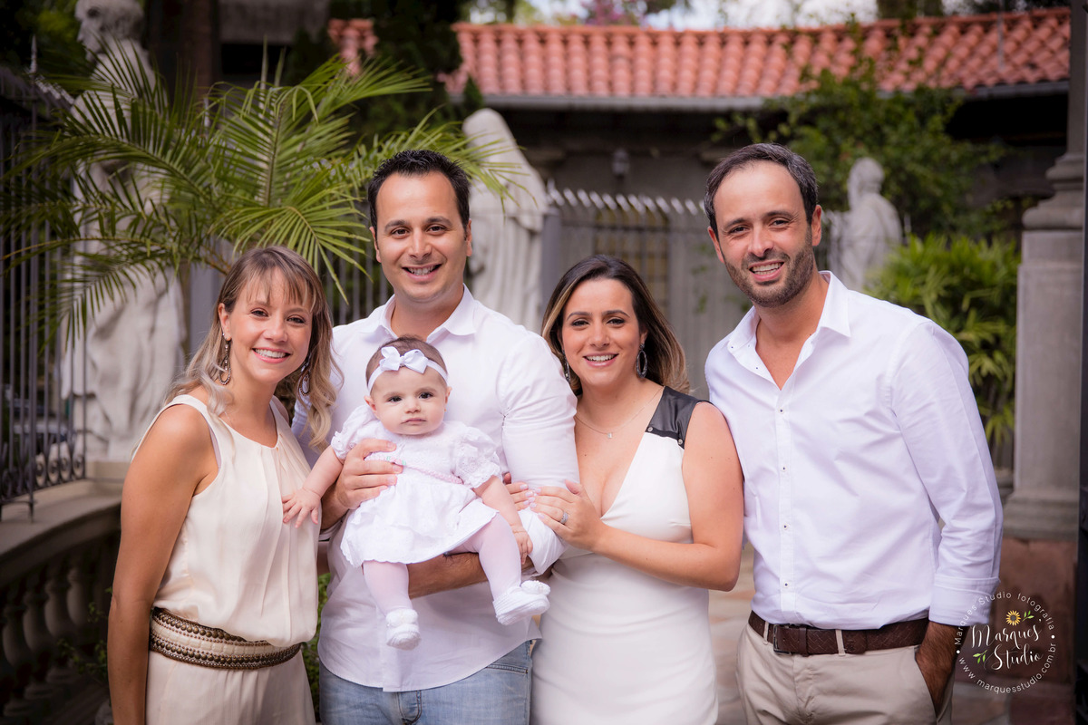Fotografia feita no batizado da Pietra, na Zona Sul de São Paulo, SP. Na foto temos os pais,  os padrinhos e a Pietra, todos estão sorridentes. 