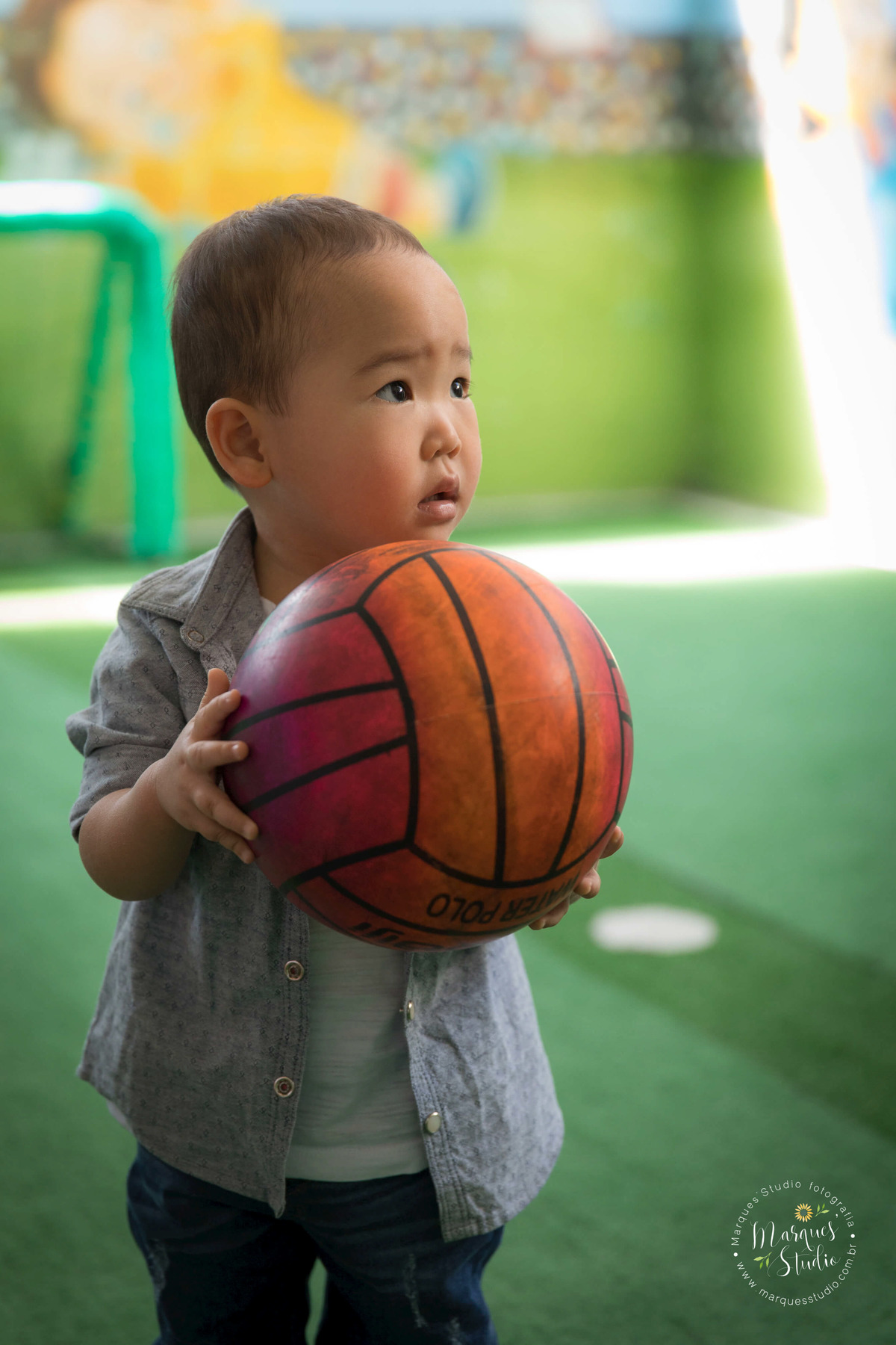 Fotografia feita no aniversário de dois anos do Rafael, em um buffet localizado em Perdizes - São Paulo, SP. Na foto temos o aniversariante brincando de bola em um campinho de futebol.