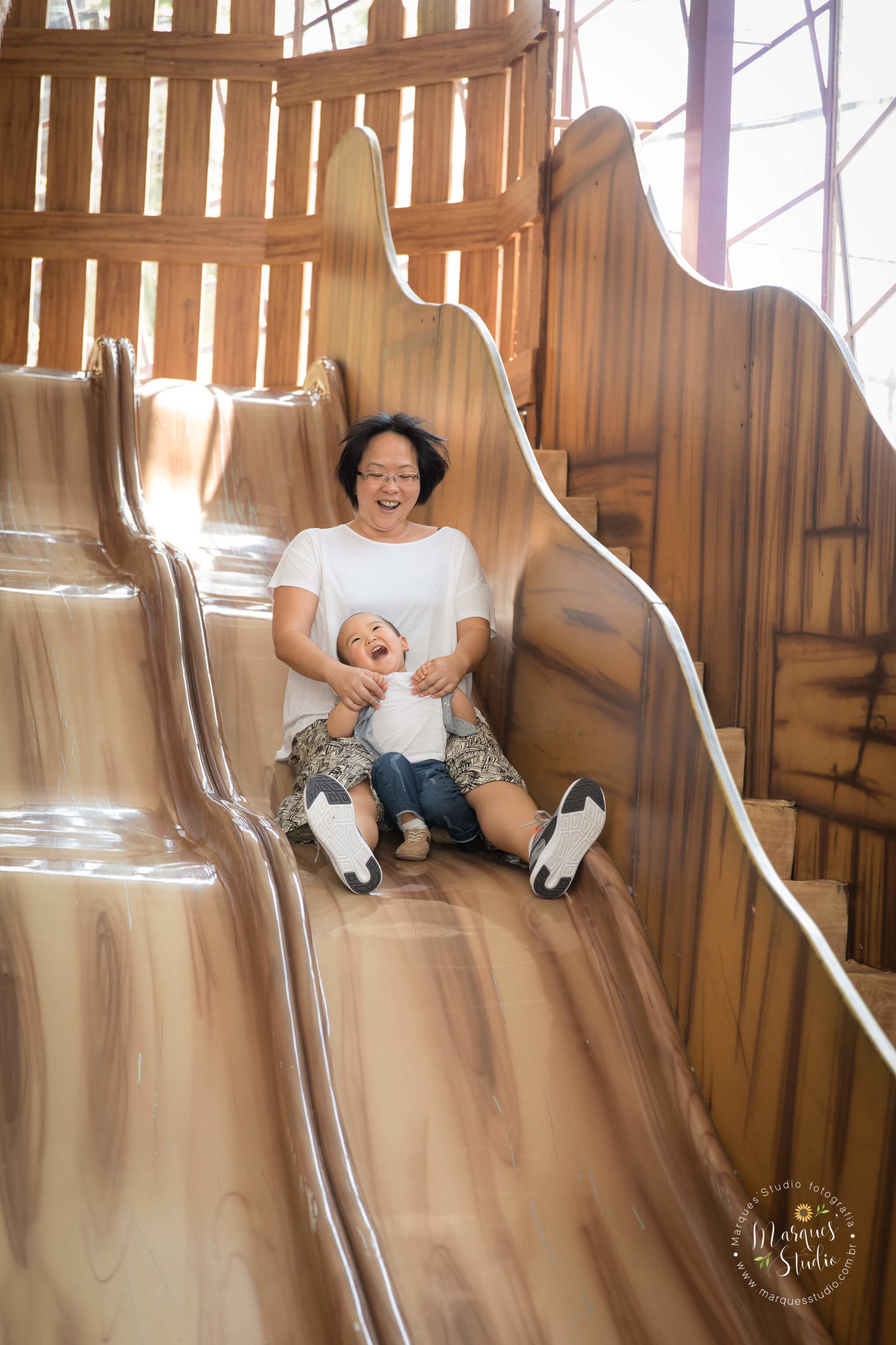 Foto feita no aniversário do Rafael de 2 anos. Na imagem temos a tia e o aniversariante brincando de descer no escorregador, eles estão muito felizes e animados. Buffet está localizado no Morumbi - São Paulo, SP