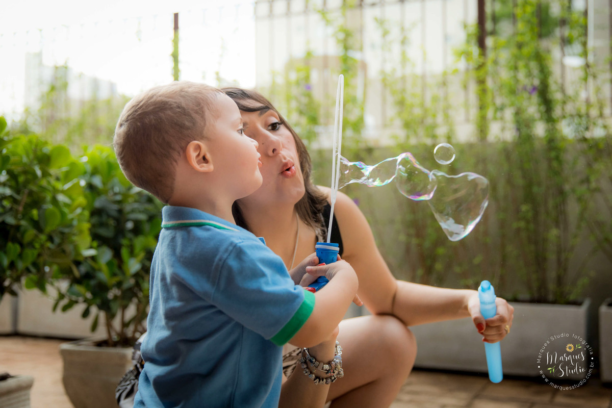 Fotografia registrada no aniversário do Guilherme de 2 aninhos. Na foto o aniversariante está brincando de soprar bolinhas de sabão com a sua mamãe, eles estão sentados no chão, em um buffet localizado em Osasco - São Paulo, SP