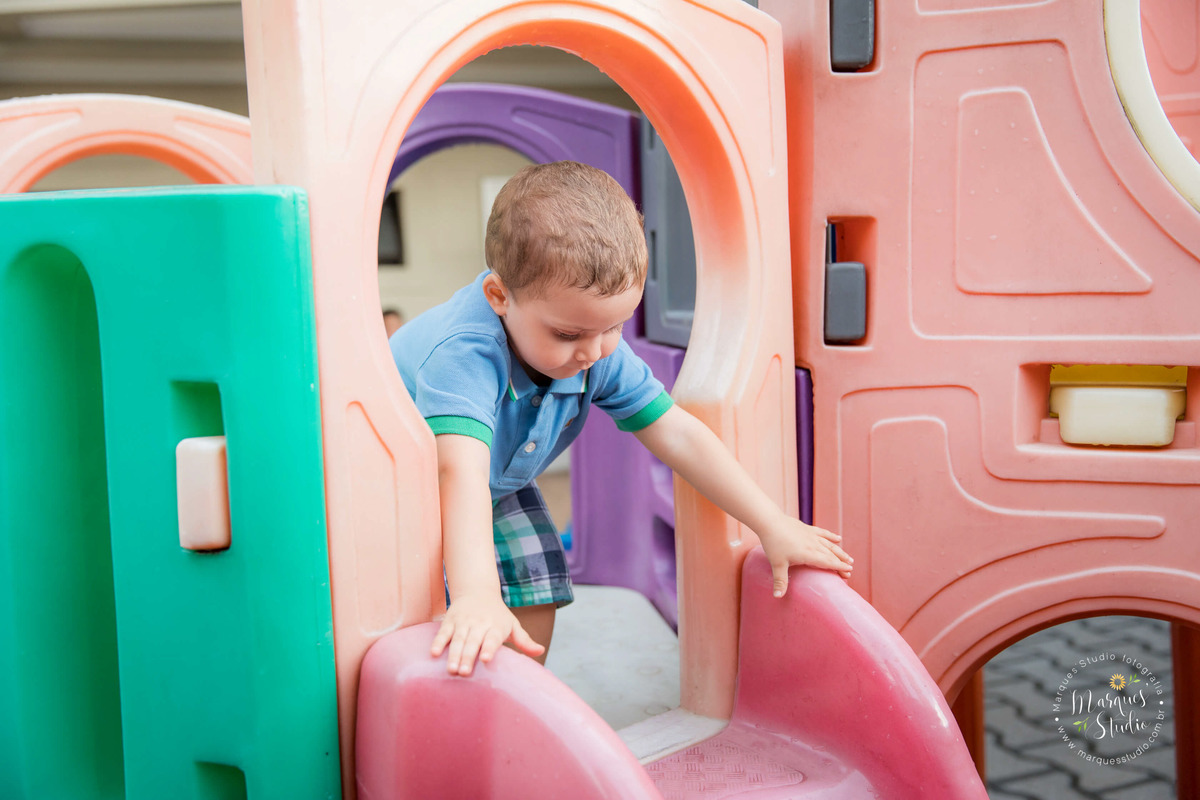 Foto tirada no aniversário do Guilherme de 2 anos em um buffet localizado na Av. Paulista - São Paulo, SP. Na foto o aniversariante está brincando em um  escorregador vermelho.