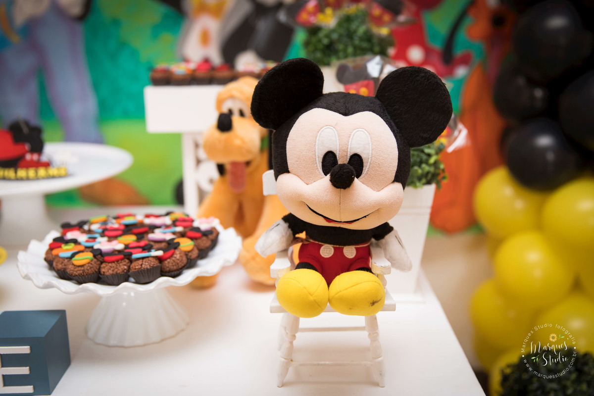 Foto tirada no aniversário do Guilherme de 2 anos em um buffet que se encontra na Vila Leopoldina - São Paulo, SP. Na foto temos parte da mesa do bolo decorada com ursinhos de pelúcia, cupcakes e muitos balões coloridos no tema do Mickey Mouse.  