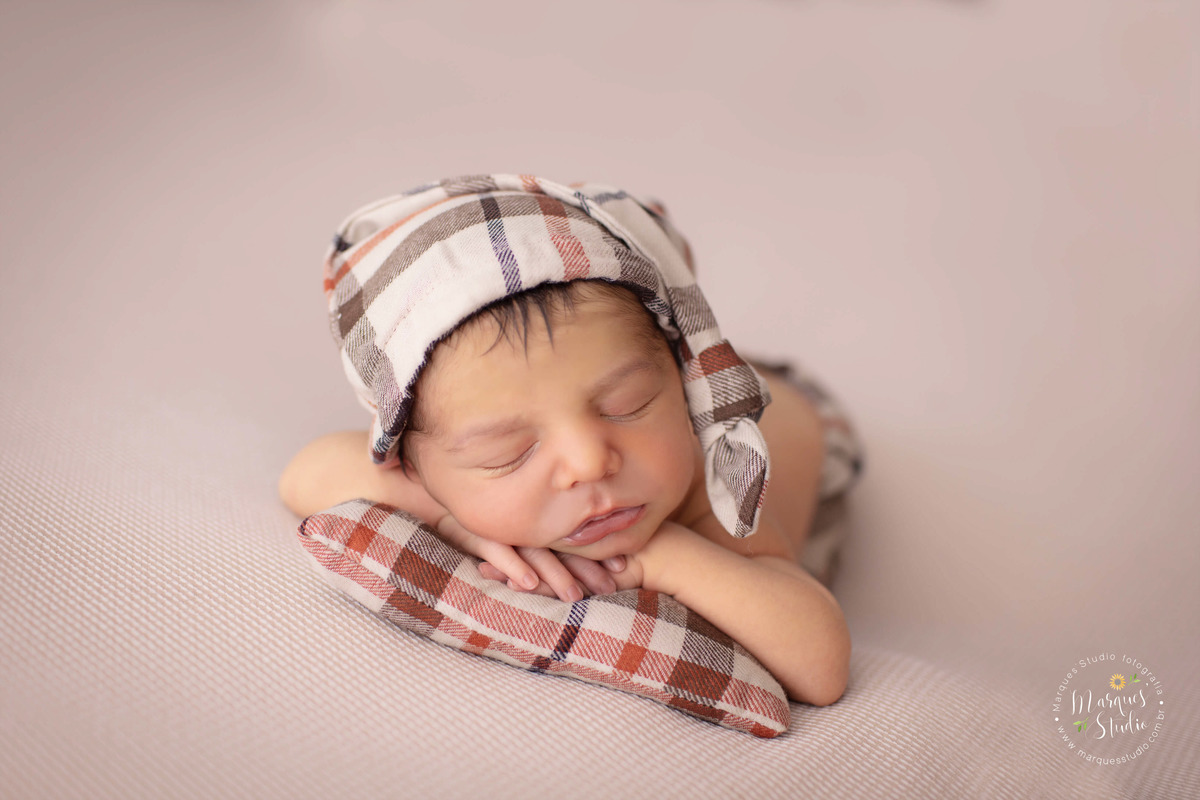 Foto tirada no ensaio Newborn do Bernardo de 6 dias no studio localizado na Vila Madalena - São Paulo, SP. Na foto temos um récem nascido deitado em um travesseiro xadrez que é a mesma estampa da sua roupa. Ele de frente, mostrando o rosto e dormindo.
